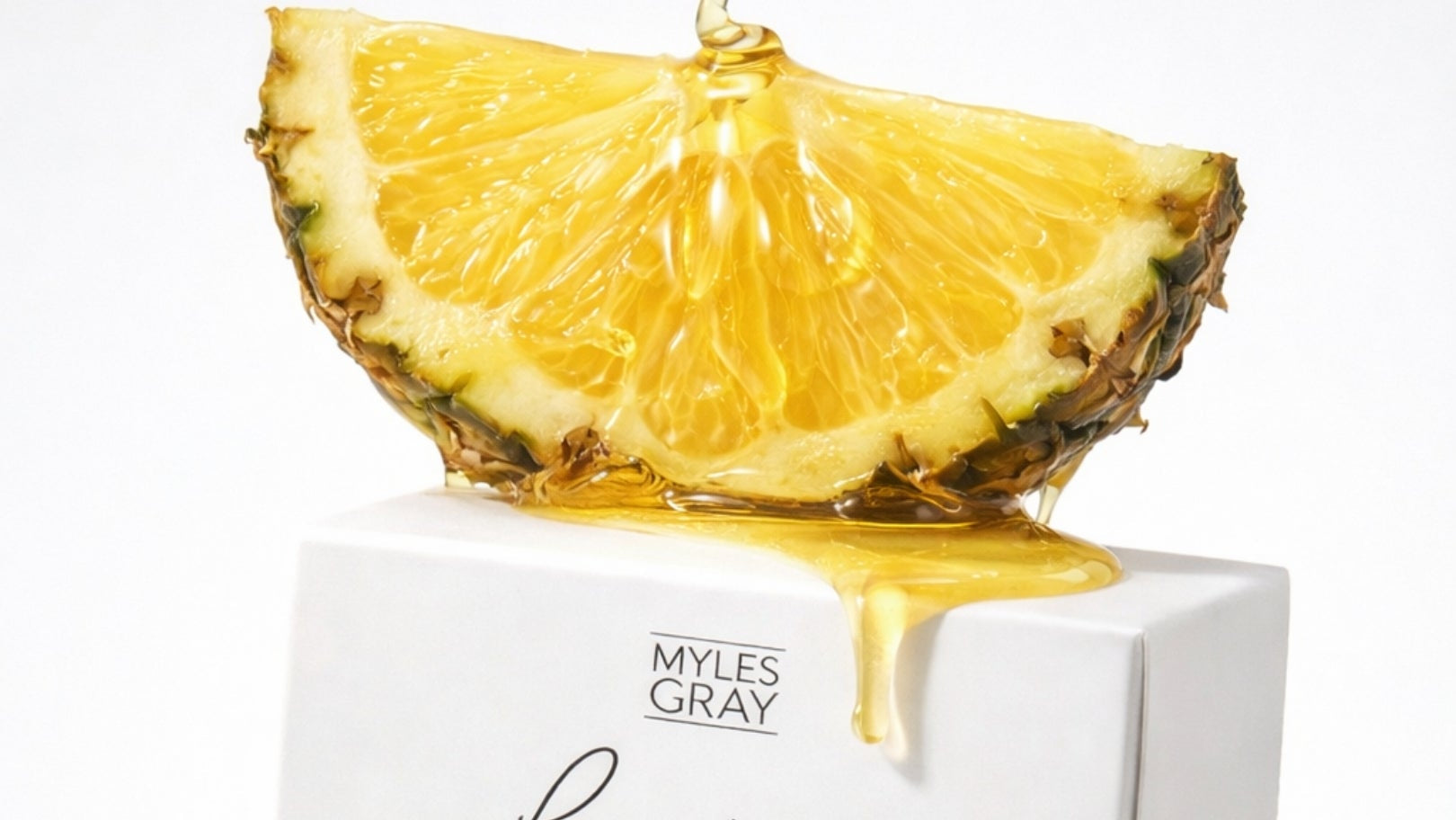 Myles Gray Lumiere candle packaging with pineapple slices and honey on a white background